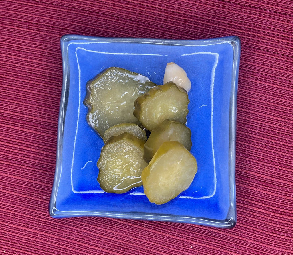 Sour cucumber pickles, fermented and full of probiotics, sitting on a blue ceramic plate