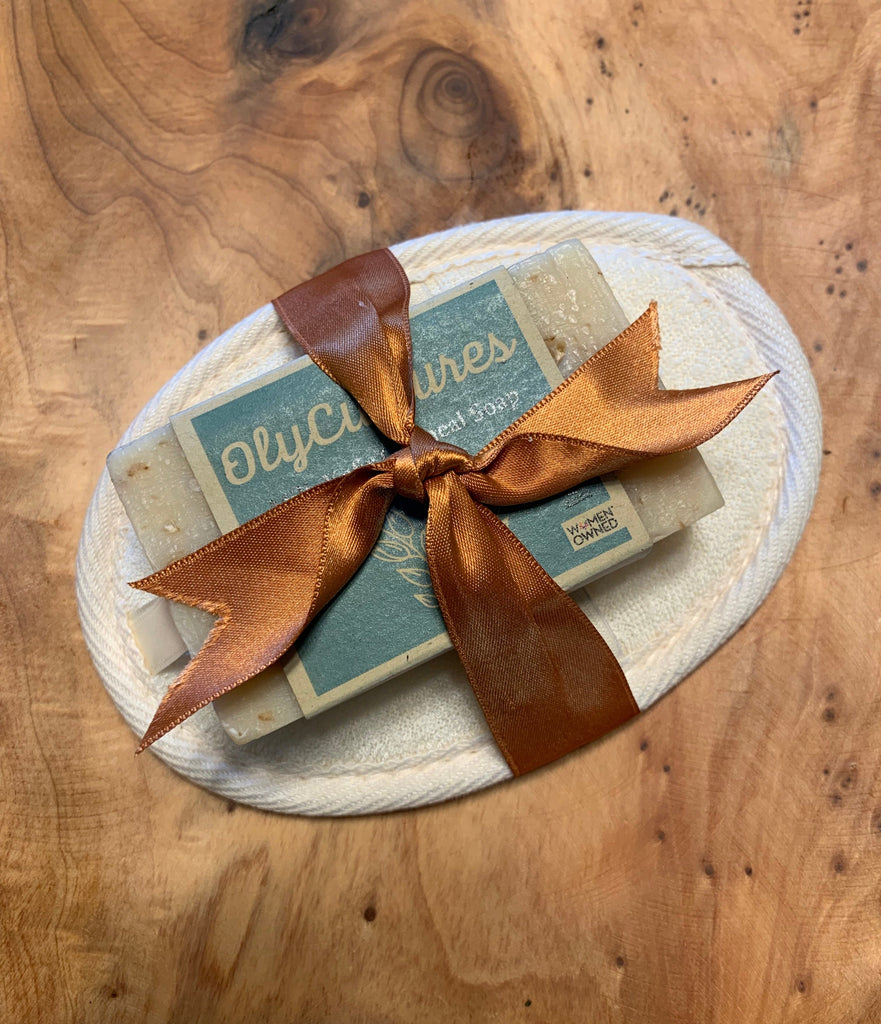 A Milk Kefir oatmeal soap bar tied onto a loofah, on a wooden background