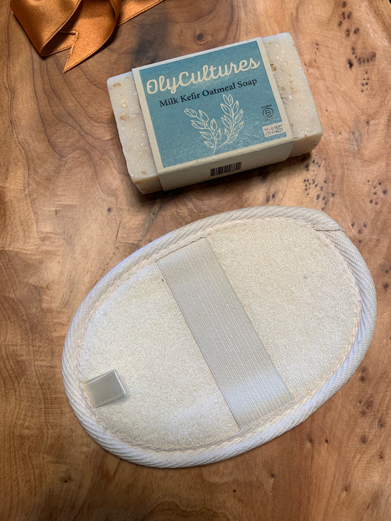 A Milk Kefir oatmeal soap bar and a natural loofah, on a wooden background